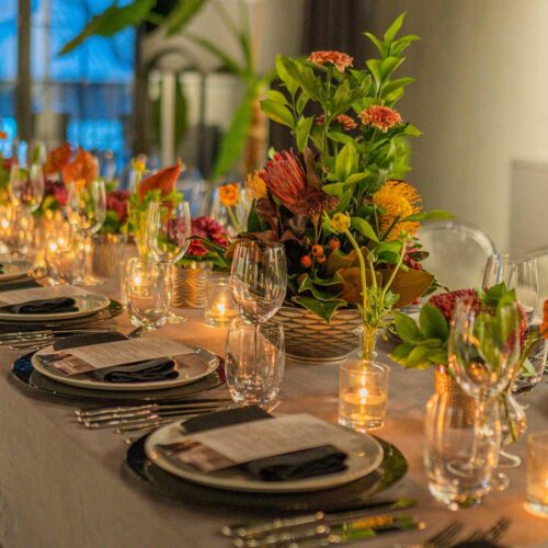 Elegant dining table setting with floral centerpieces, candles, glassware, and place settings prepared for a special event or dinner party.