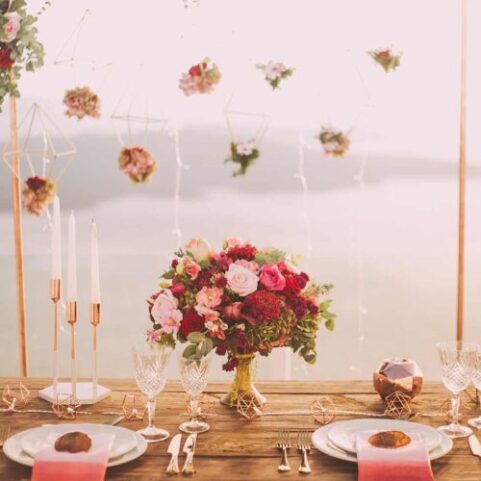 Elegant table setting with colorful floral arrangements, modern design, at a wedding or event in Orange County; candles, and glassware.