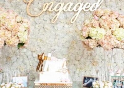 legant floral arrangements. The backdrop is a wall covered in flowers with balloons on either side, creating an opulent atmosphere.