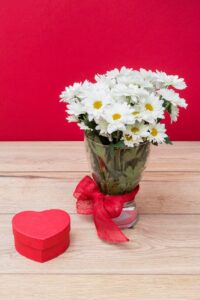 Heart-shaped gift box with a bouquet of daisies in a vase